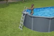 Volwassene stapt uit een opblaasbaar zwembad op een groene tuin.