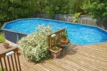 Zwemvijver in tuin met houten terras, omgeven door groen en planten, ideaal voor zomerse ontspanning.