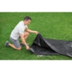 Man zet een zwembadliner op grasveld klaar voor installatie.