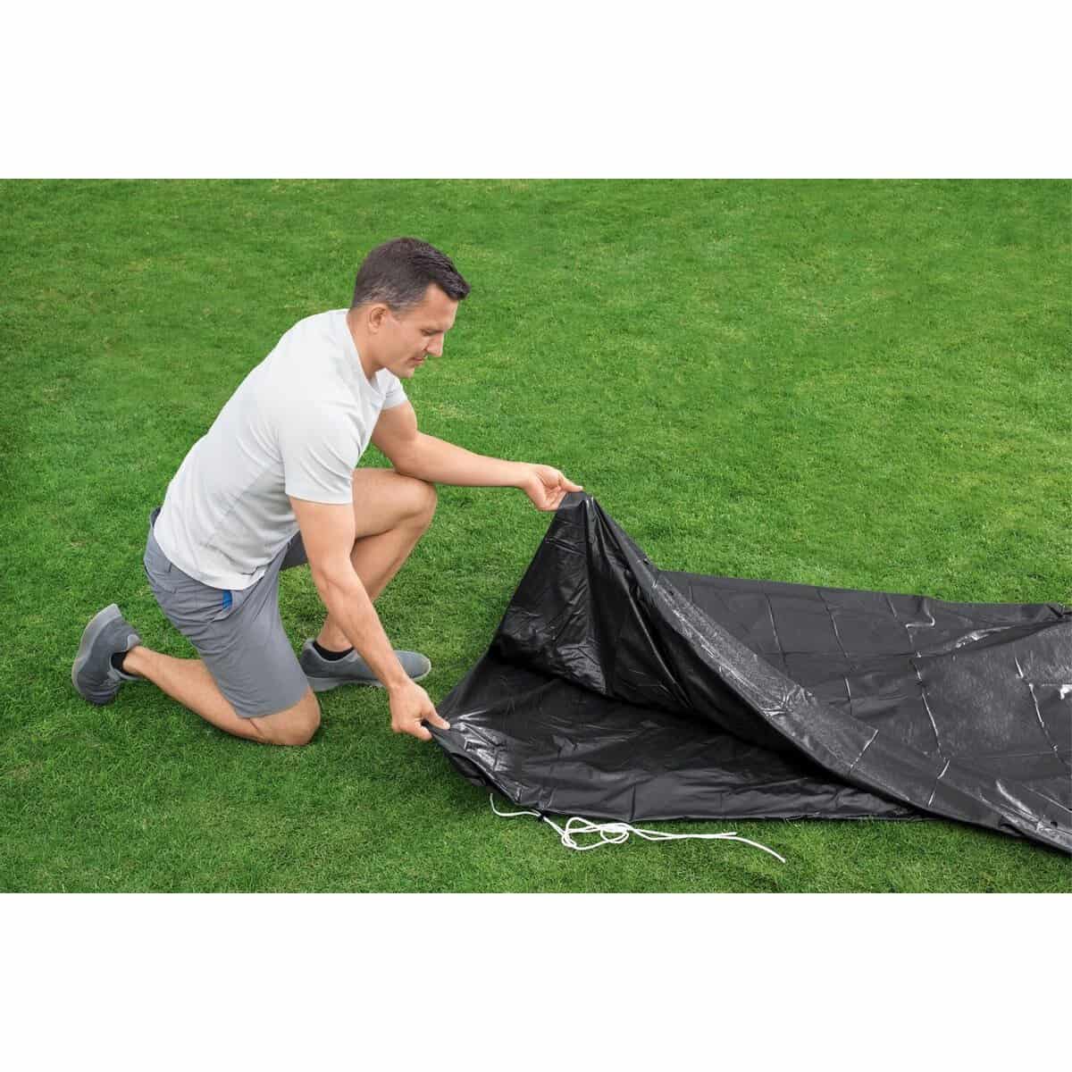 Man zet een zwembadliner op grasveld klaar voor installatie.