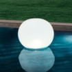 Zwemmerlamp in de vorm van een grote witte bol drijft op het water van het zwembad.
