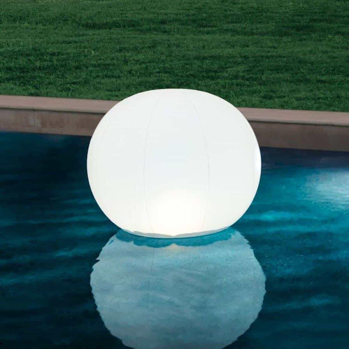 Zwemmerlamp in de vorm van een grote witte bol drijft op het water van het zwembad.