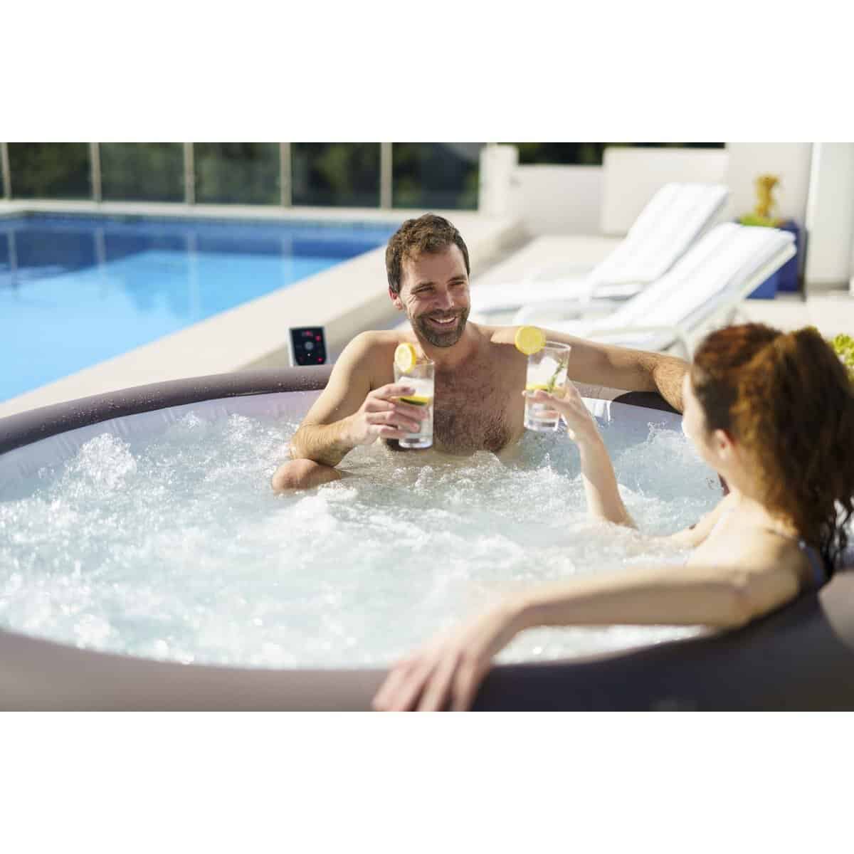 Man en vrouw genieten van een hottub met drankjes in de tuin.