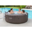 Opblaasbare hottub met vier mensen die genieten in de tuin.