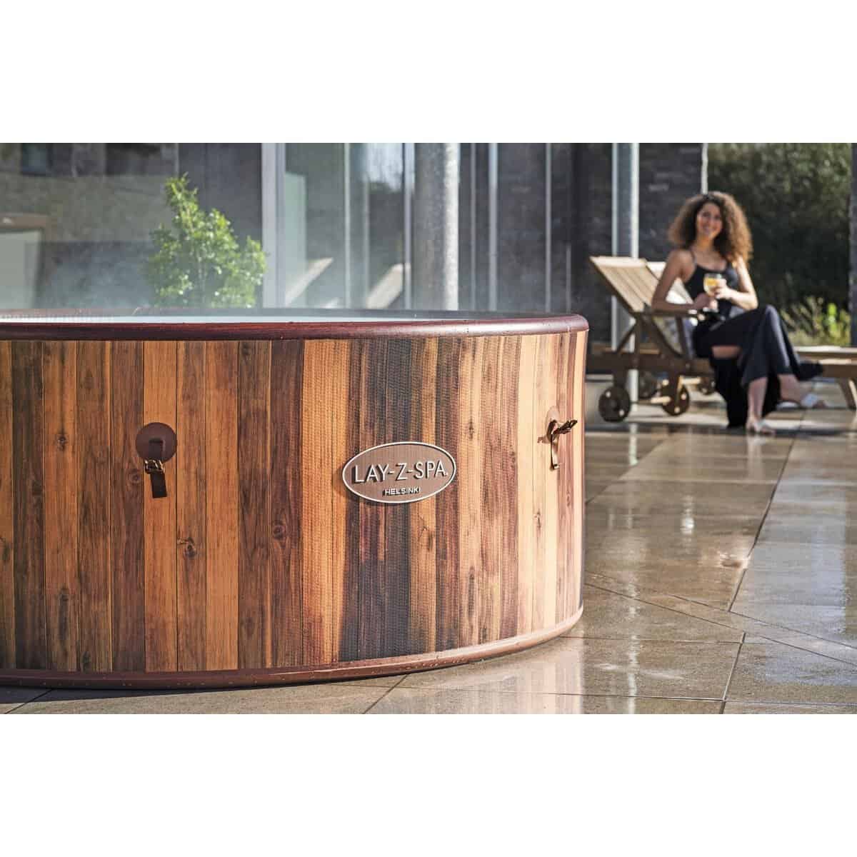 Houten hottub voor buitengebruik met vrouw die ontspant op ligstoel.