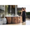 Luxe houten hottub buiten met stoom, vrouw genietend van ontspanning.