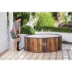 Houten hottub voor buitengebruik op terras met tuin en bloemen.