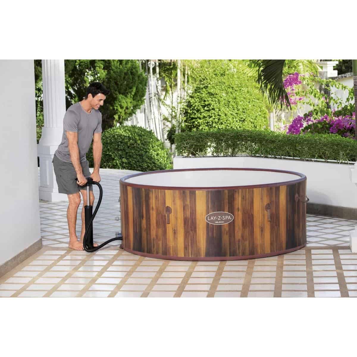 Houten hottub voor buitengebruik op terras met tuin en bloemen.