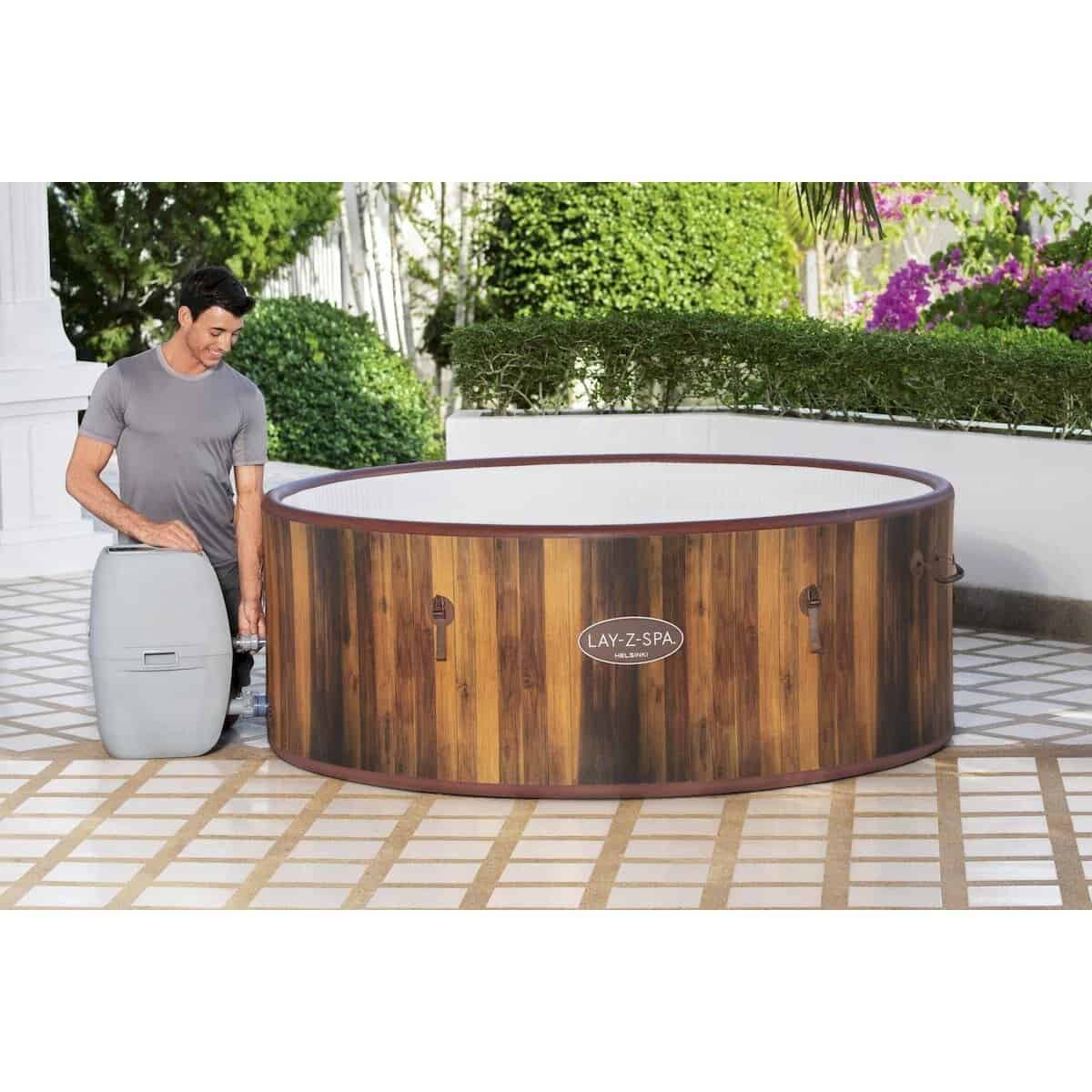 Luxe houten hottub op terras met groene tuin en bloemen.