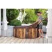 Luxe houten hot tub buiten in tuin met man die de cover verwijdert.