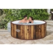 Houten hottub in tuin met twee mensen die genieten van ontspanning.