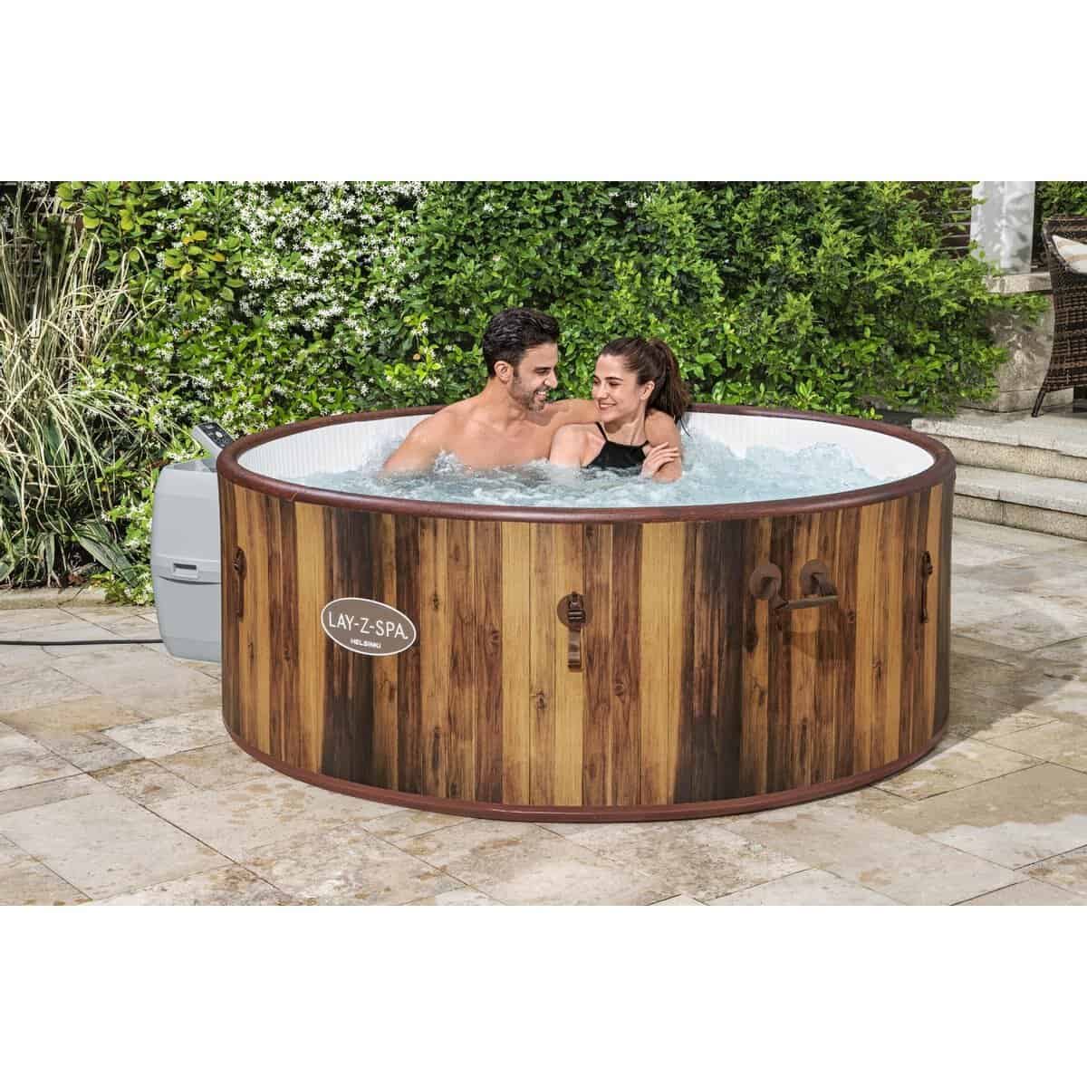 Houten hottub in tuin met twee mensen die genieten van ontspanning.